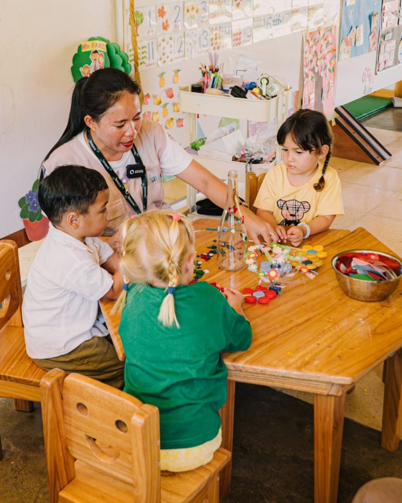 Students engaged in play-based learning with a teacher at Biosphere Bali School, using creative materials in a Cambridge and Finnish-Asian curriculum setting